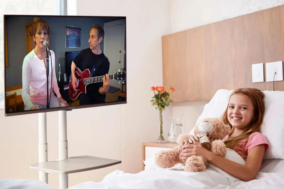 A young patient watching Harmony & Healing musicians perform live over video