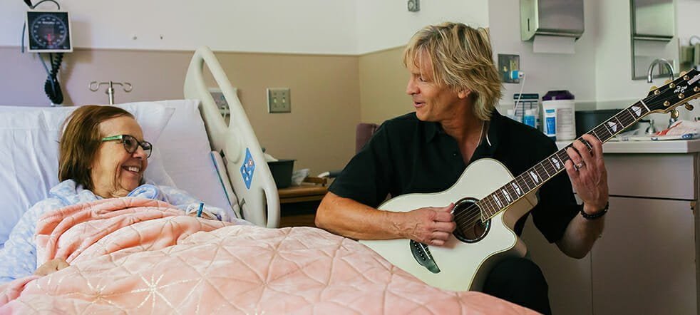 Harmony & Healing main photo showing musician singing to patient