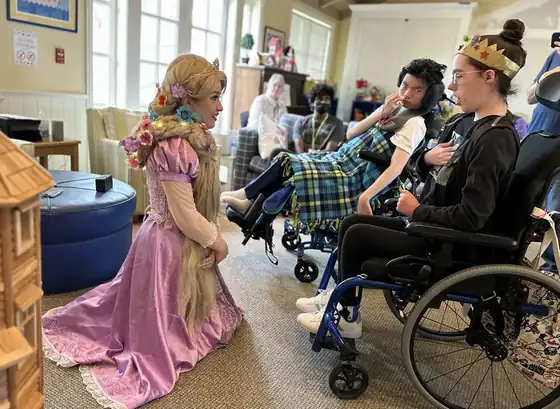 Performer in pink gown entertaining patients in wheelchairs at healthcare facility during Harmony & Healing live music event